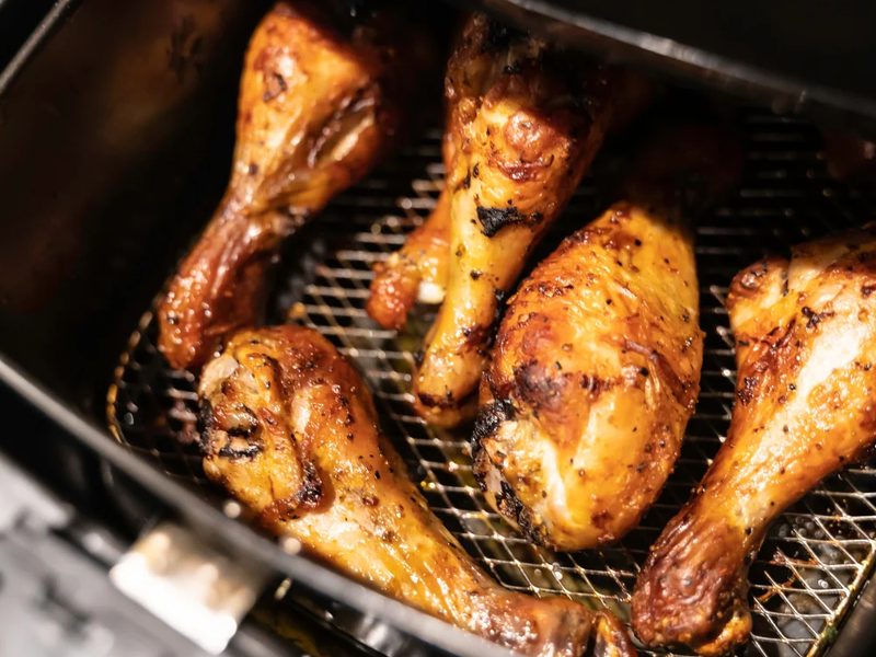 Goudbruine drumsticks op het rooster in een airfryer