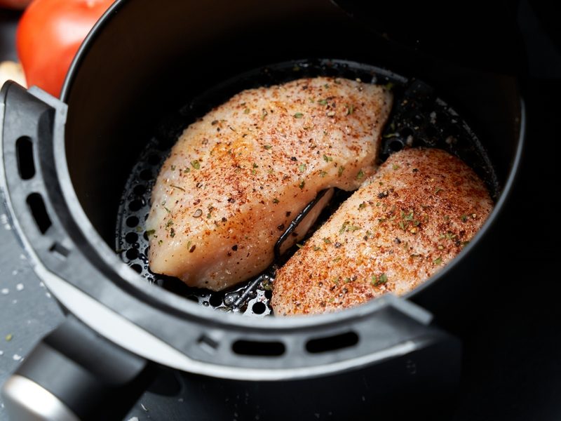Twee gekruide kipfilets in de mand van een airfryer
