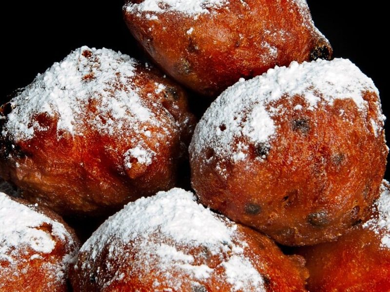 Stapel oliebollen met rozijnen, bestrooid met poedersuiker